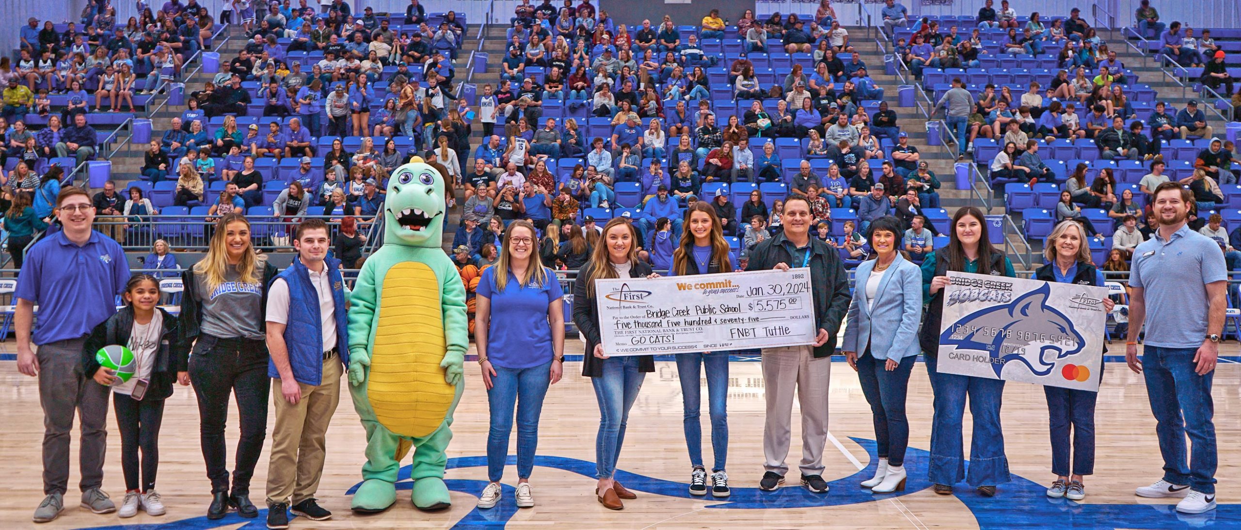Image of bankers presenting a check to the school superintendent at a basketball game.